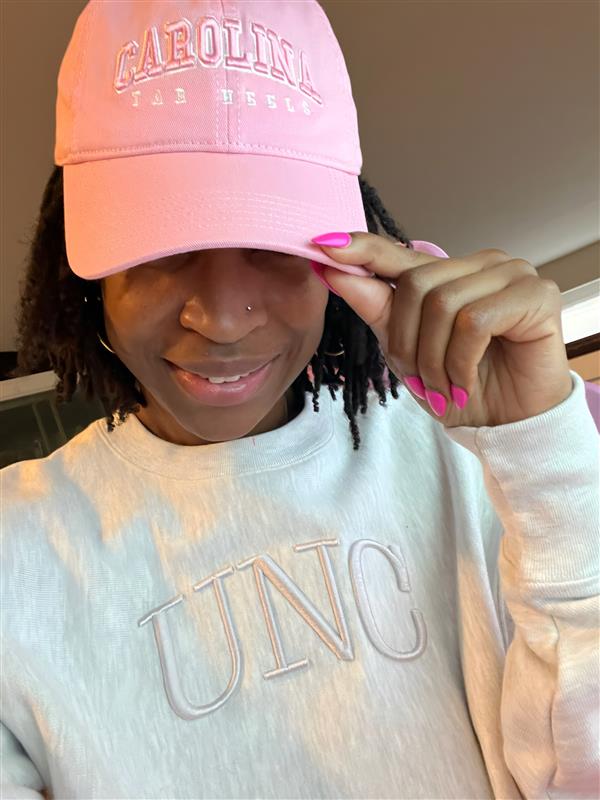 Stefanee Richardson wearing a pink UNC hat and sweatshirt, celebrating the start of her MBA Leadership Journal at Kenan-Flagler.